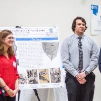 A student team stands by their poster presentation